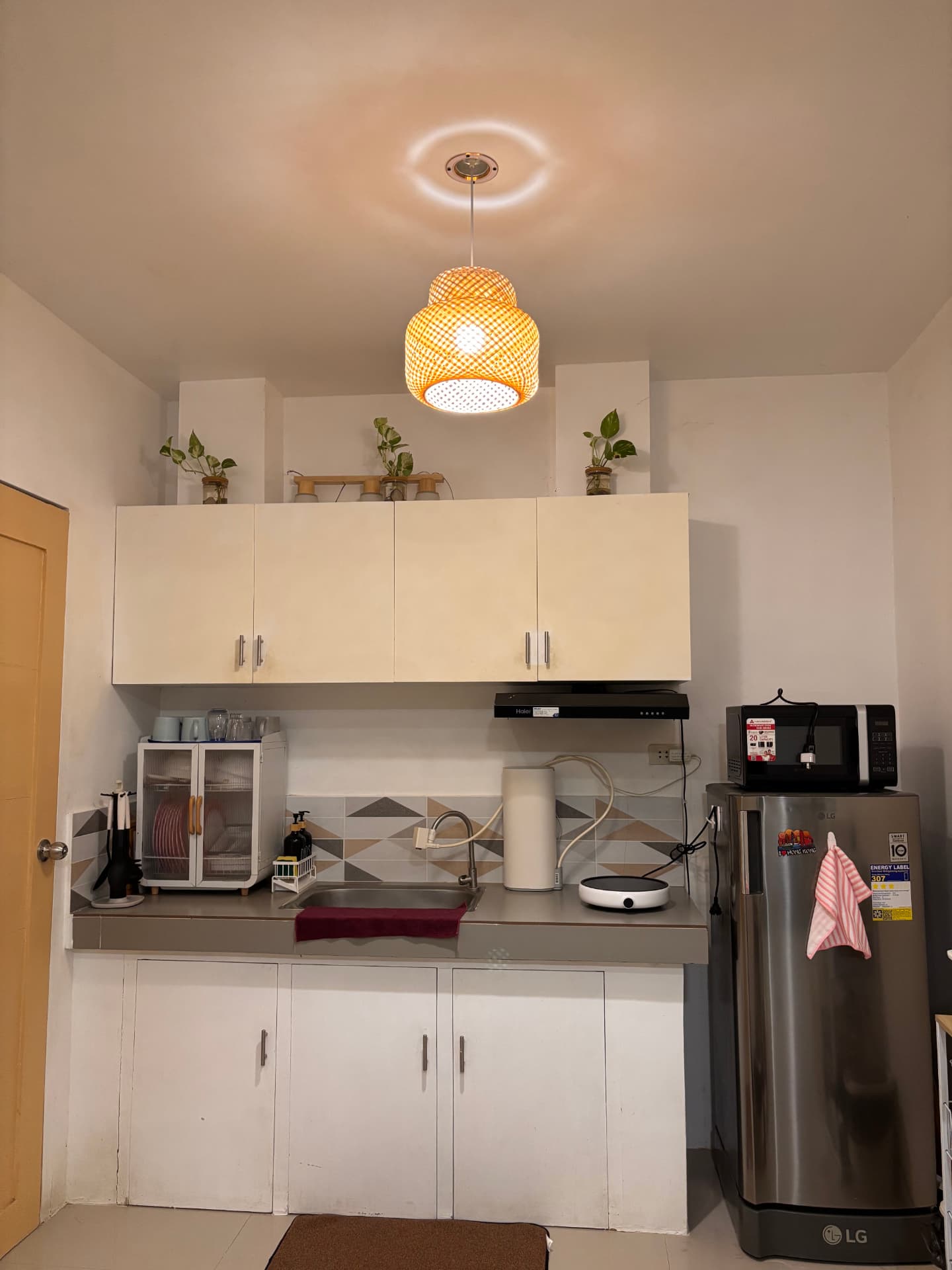 Kitchen counter with sink, cabinets, refrigerator, and rattan pendant light